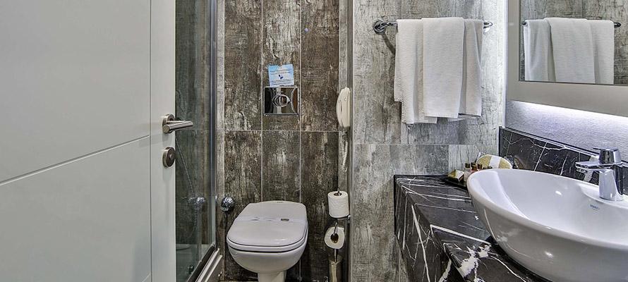 Badezimmer im Saturn Palace Resort mit Dusche, Toilette, Waschbecken und Handtüchern.