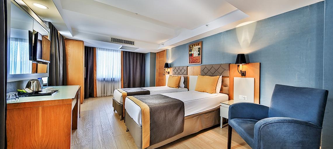 Doppelzimmer im Saturn Palace Resort mit zwei Betten, einem Nachttisch, einem Schreibtisch und einer modernen Einrichtung.
