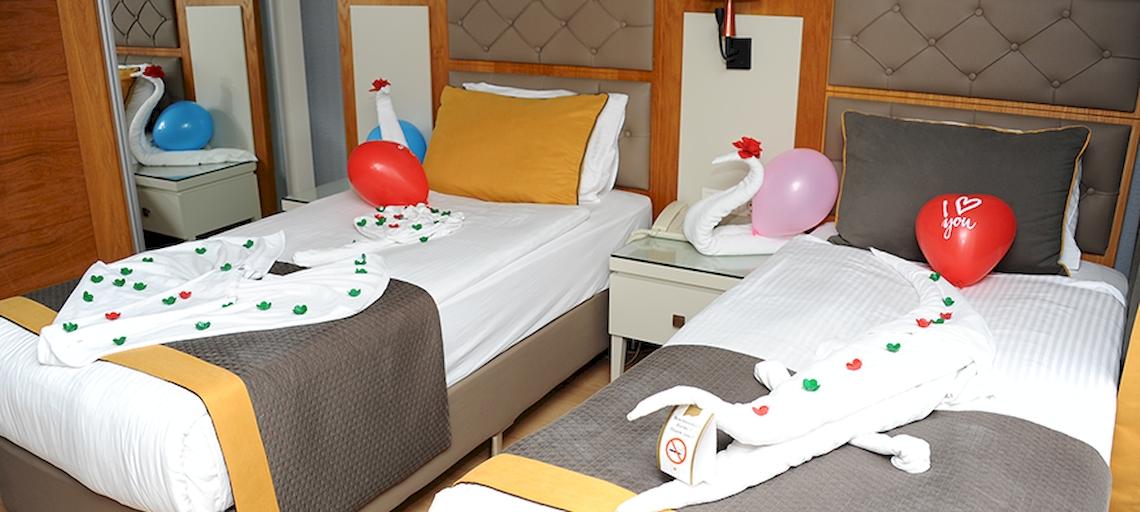 Zwei Betten im Saturn Palace Resort mit roten Ballons und Liebesbotschaften.