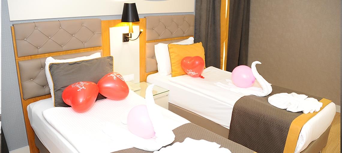 Zwei Zimmer im Saturn Palace Resort mit roten Herz-Ballons und weißen Handtüchern.