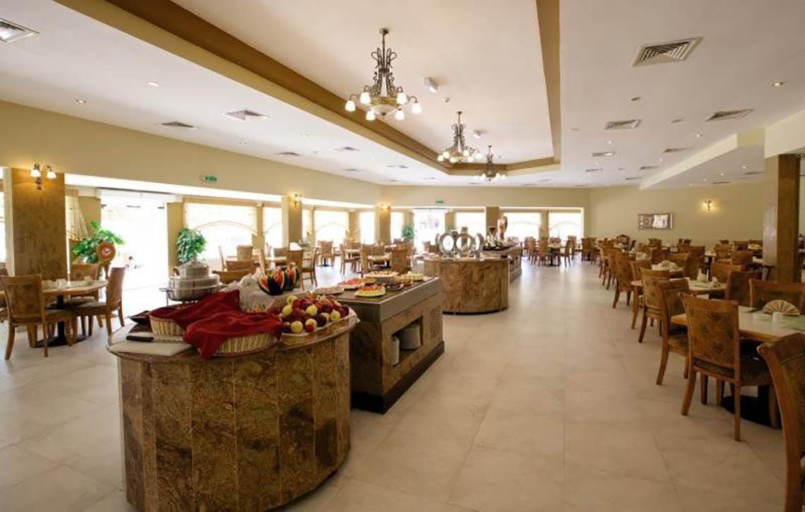 Innenansicht des Restaurants im BM Beach Hotel mit Buffet, Tischen und Stühlen.