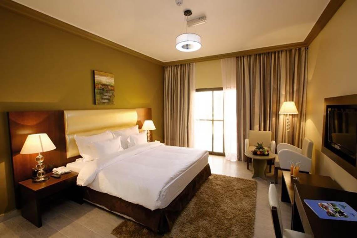 Doppelzimmer im BM Beach Hotel mit bequemem Bett, Nachttischen, Lampen und Fernseher.
