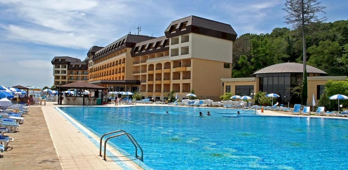Außenpool des Riviera Beach Hotel mit umliegenden Lounge-Stühlen und Sonnenschirmen.