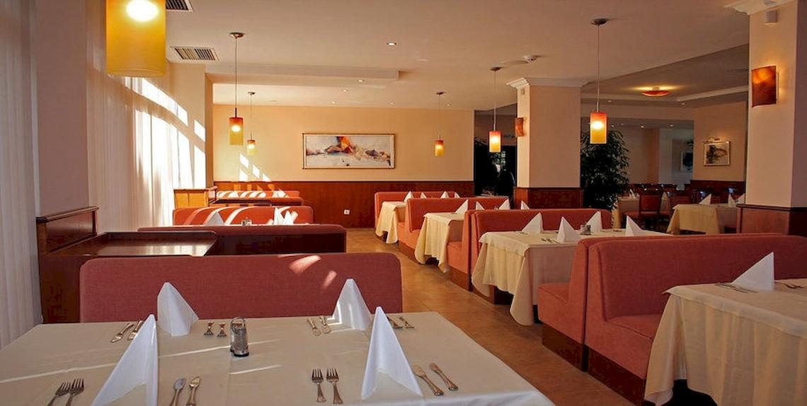 Innenbereich des Restaurants im Riviera Beach Hotel mit gepolsterten roten Sitzen und weiß gedeckten Tischen.
