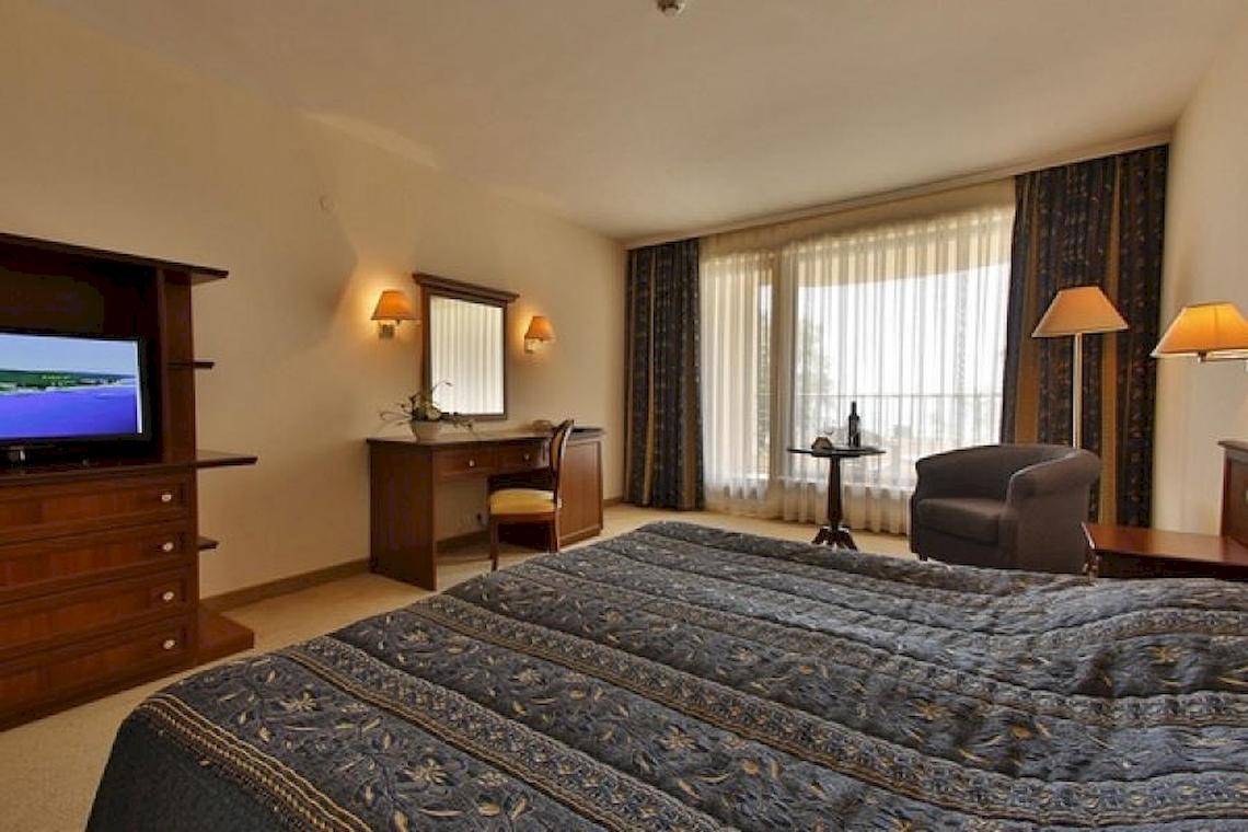 Zimmer im Riviera Beach Hotel mit Doppelbett, Fernseher, Schreibtisch und Stühle.