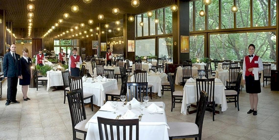 Innenbereich des Riviera Beach Hotel Restaurants mit gedeckten Tischen und wartendem Personal.