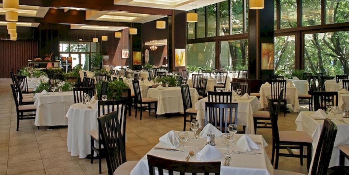 Innenansicht des Restaurants im Riviera Beach Hotel mit gedeckten Tischen und Stühlen.