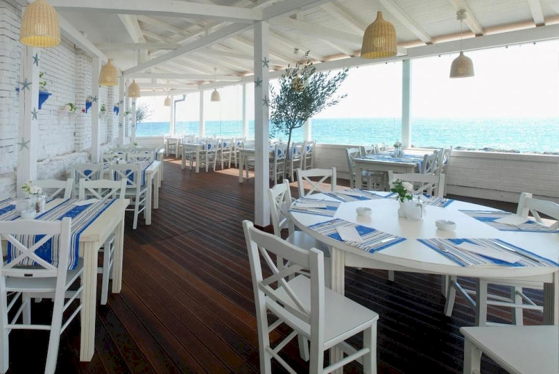 Terrasse des Riviera Beach Hotels mit Blick auf das Meer und weißen Möbeln.