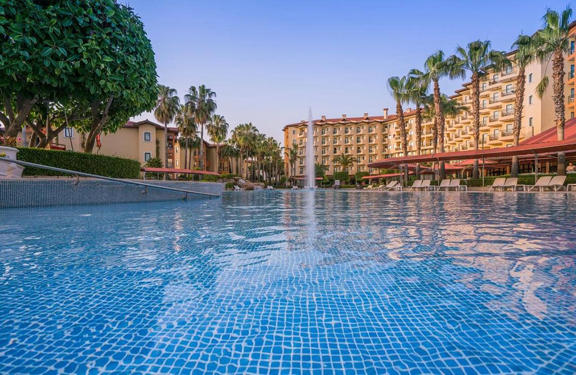Außenpool des Miramare Queen Hotels mit Palmen und Sonnenliegen