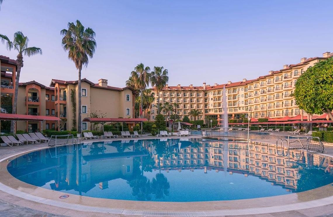 Außenansicht des Miramare Queen Hotels mit Swimmingpool und Sonnenliegen.