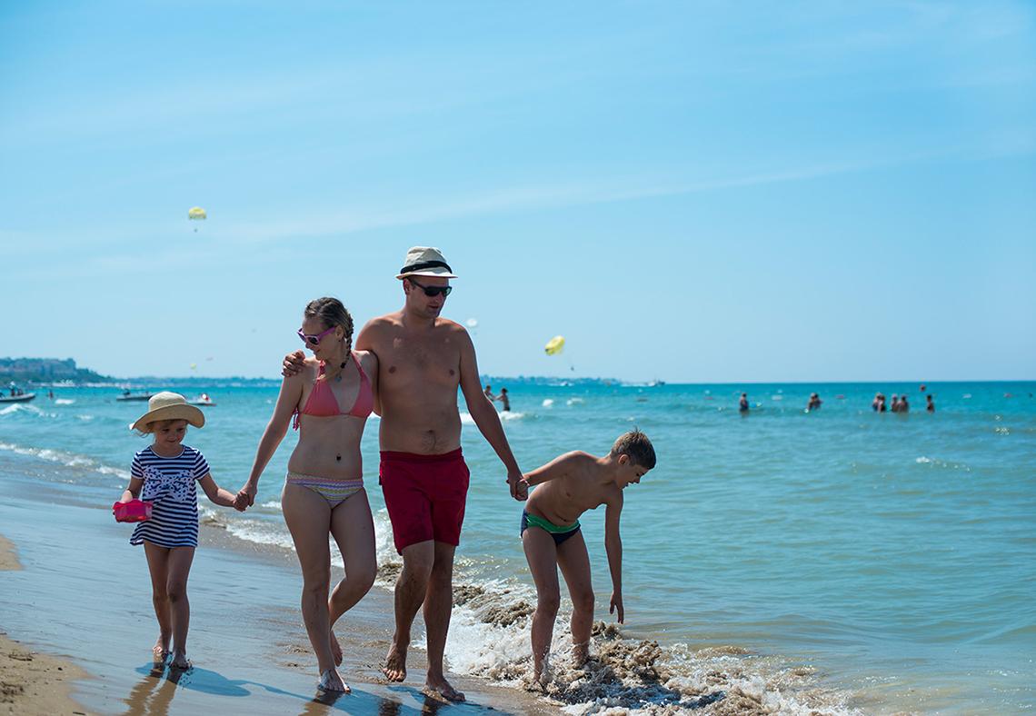 Eine Familie, die am Strand spazieren geht, genießt einen sonnigen Sommertag.