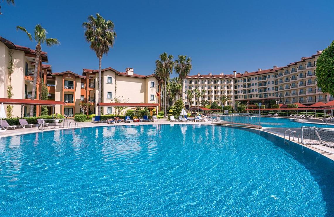 Außenbereich des Miramare Queen Hotels mit Swimmingpool und Sonnenliegen.