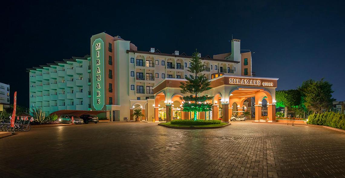 Miramare Queen Hotel bei Nacht mit leuchtenden Neonschildern und beleuchteter Einfahrt