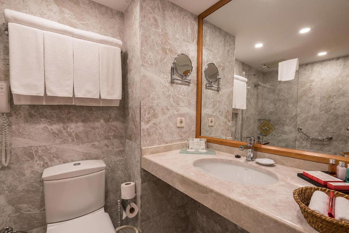 Badezimmer im Miramare Queen Hotel mit Toilette, Waschbecken, Spiegel und Handtüchern.