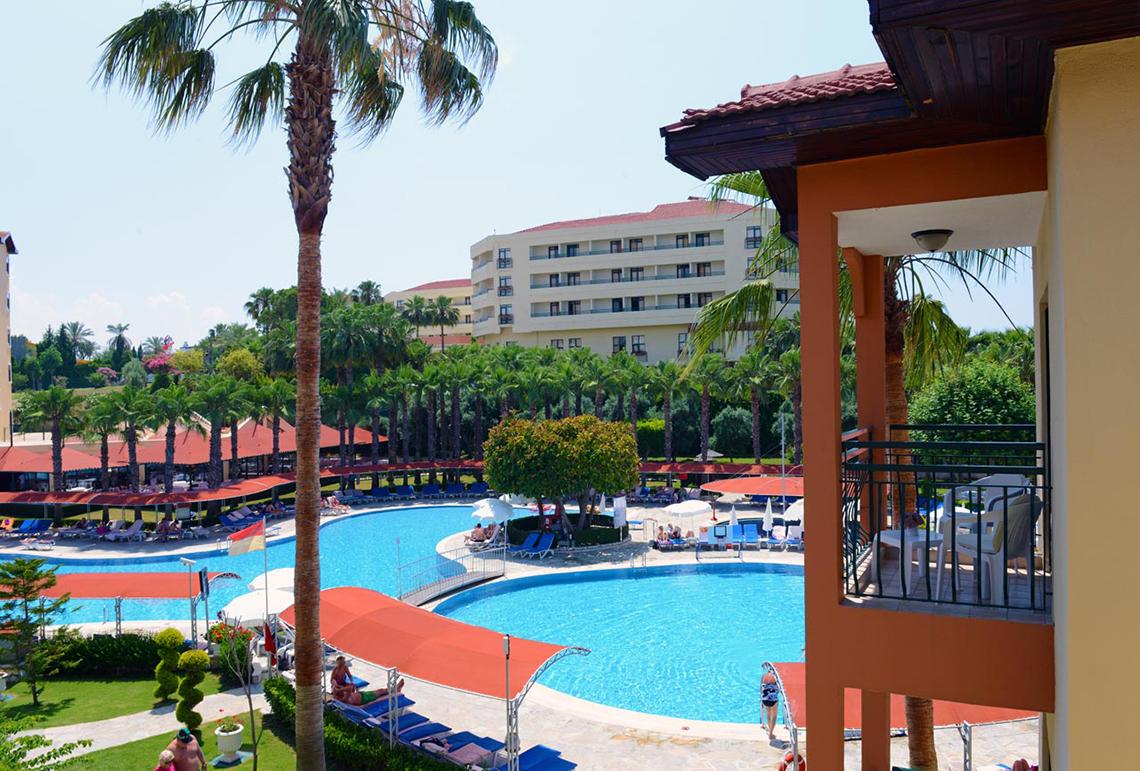 Außenbereich des Miramare Queen Hotels mit Swimmingpool, Liegestühlen und Gebäuden