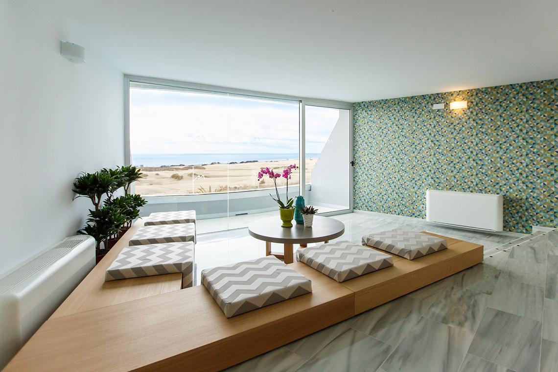 Innenraum des Santa Monica Suites mit Loungebereich, großen Fenstern und Meerblick.