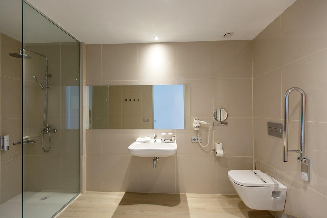 Badezimmer im Santa Monica Suites Hotel mit Dusche, Waschbecken und Toilette.