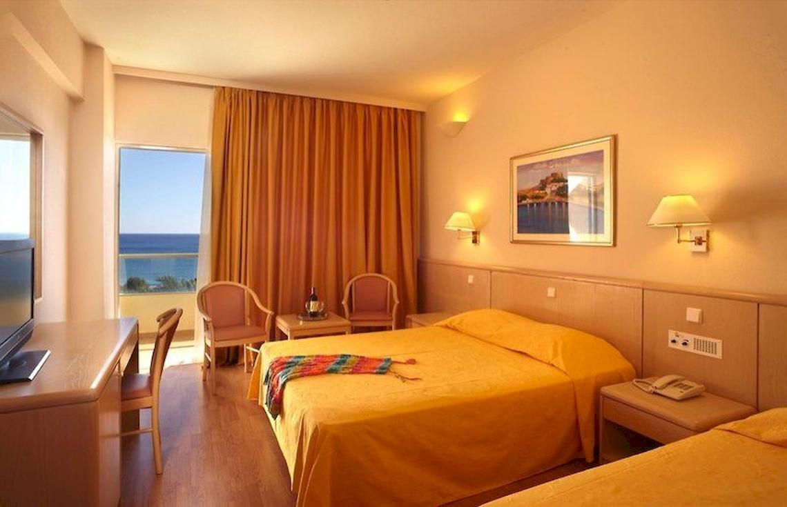 Hotelzimmer des Blue Sea Beach Resort mit Blick auf das Meer, zwei Betten, Schreibtisch und Fernseher.