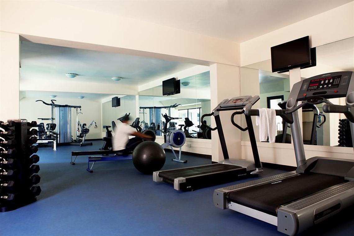 Fitnessstudio im Golden Sands Hotel Apartments mit Trainingsgeräten und Spiegeln.