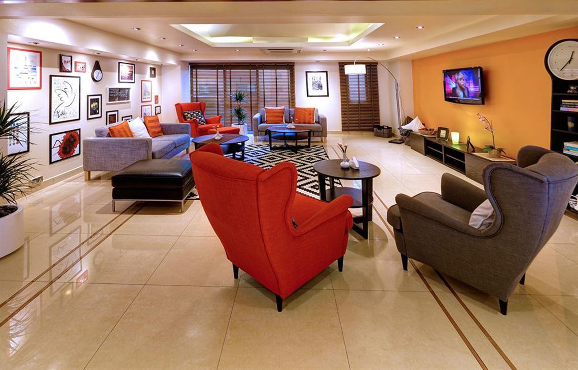 Wohnbereich des Golden Sands Hotel Apartments mit Sitzmöbeln, Fernseher und Dekoration.