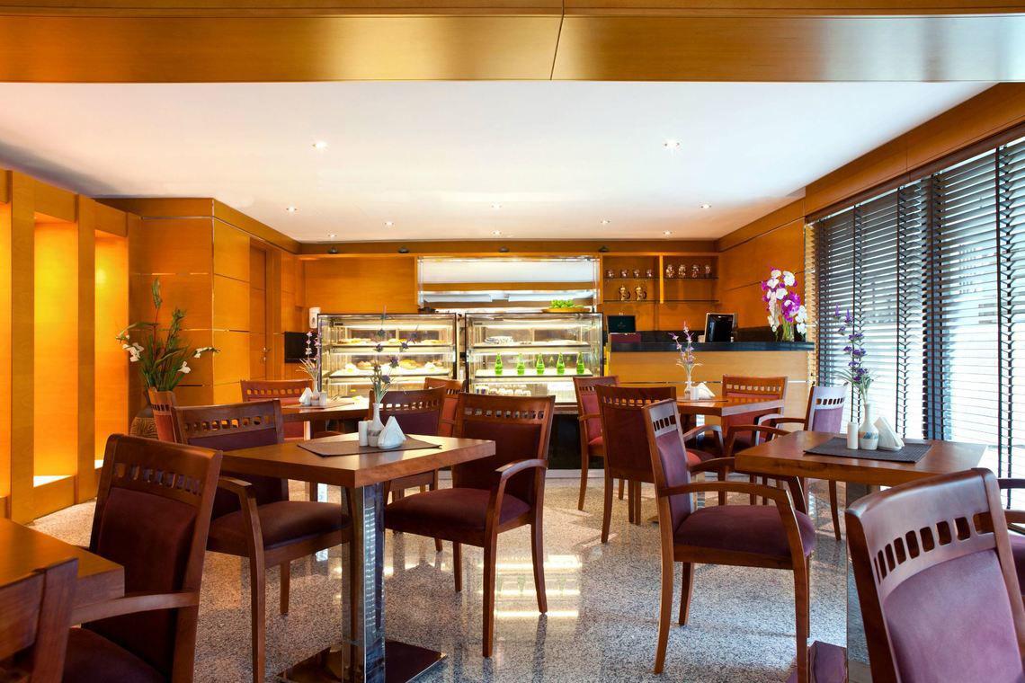 Innenansicht des Restaurants im Golden Sands Hotel Apartments mit Holztischen und Stühlen.