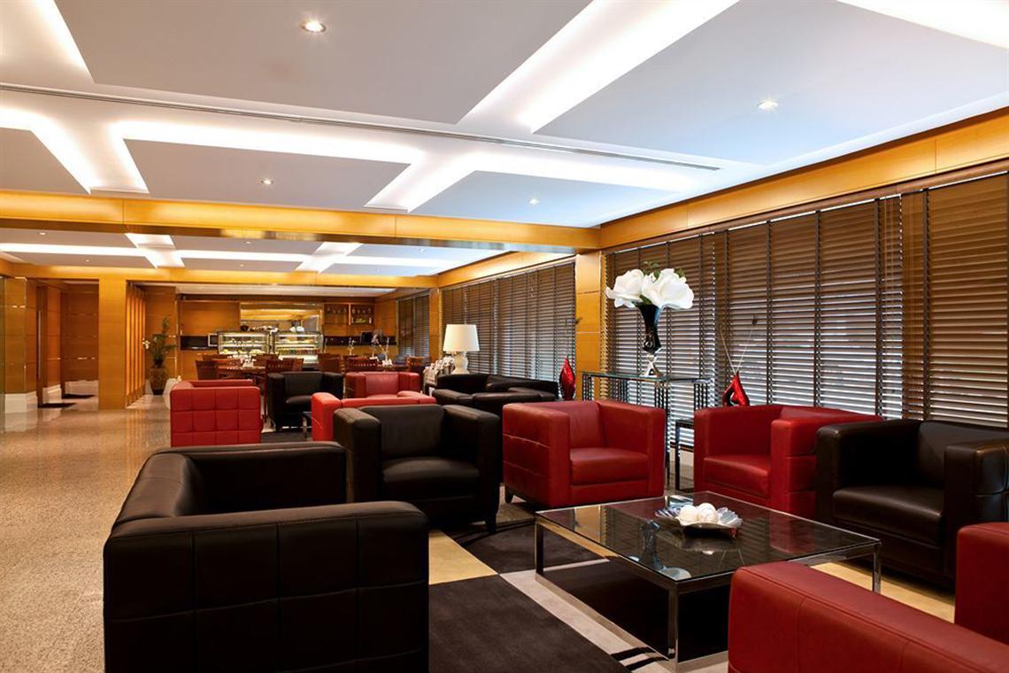 Loungebereich des Golden Sands Hotel Apartments mit roten und schwarzen Ledersesseln.