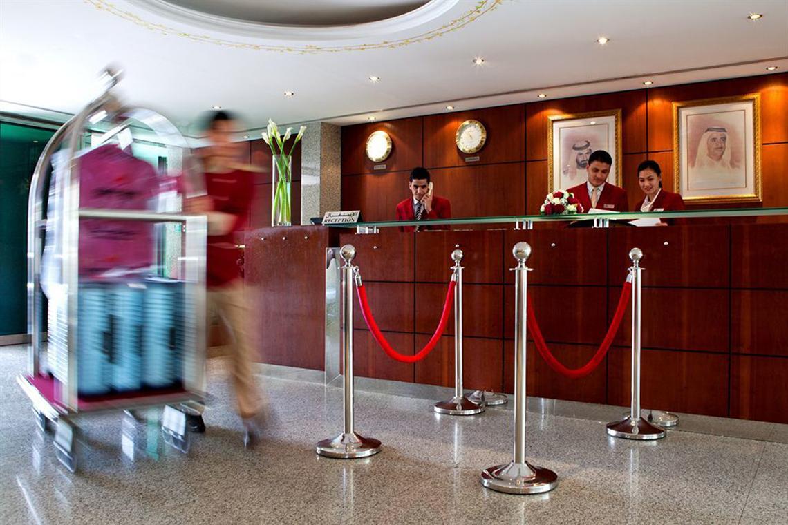 Reception des Golden Sands Hotel Apartments mit Mitarbeitern und einem Gast, der ein Gepäckkarr rollt.