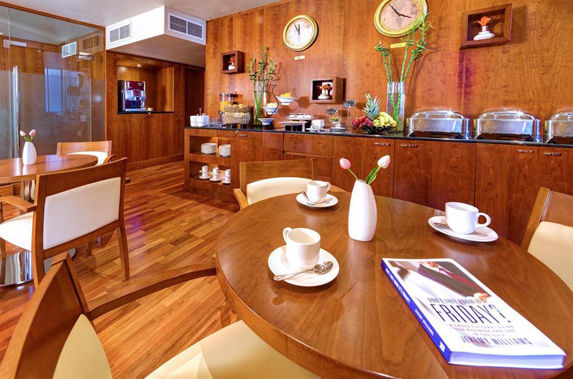 Frühstücksbereich im Golden Sands Hotel Apartments mit Holzmöbeln und Frühstücksbuffet.