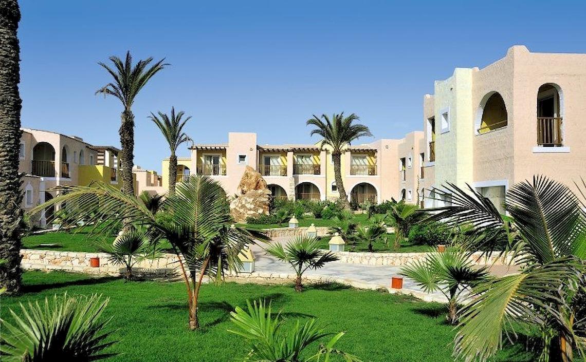 Außenbereich des VOI Praia De Chaves Resort mit Gebäuden, Palmen und Rasen.