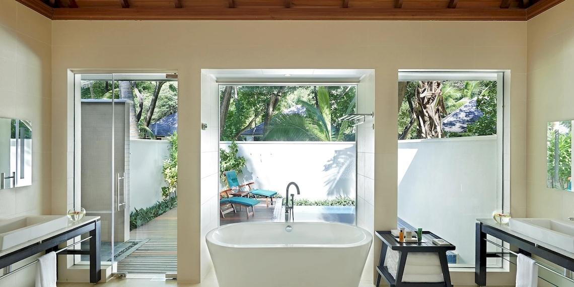 Badezimmer im Hilton Seychelles Labriz Resort & Spa mit Badewanne, Dusche und Blick auf den Garten.