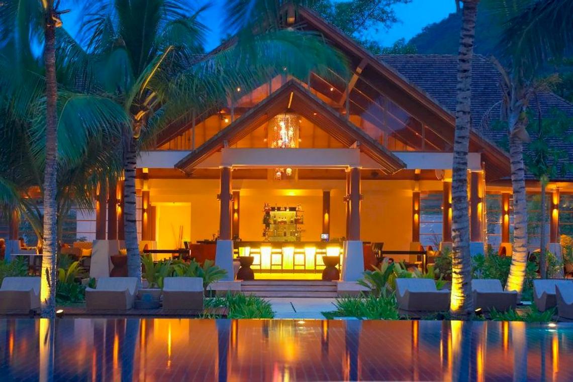 Außenansicht des Hilton Seychelles Labriz Resort & Spa bei Nacht mit beleuchteter Bar und Loungebereichen.