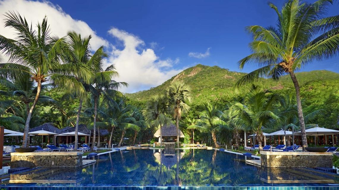 Poolbereich des Hilton Seychelles Labriz Resort & Spa mit Blick auf die Palmen und Berge