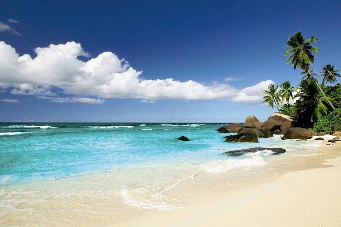 Strand des Hilton Seychelles Labriz Resort mit blauem Wasser und weißen Sand