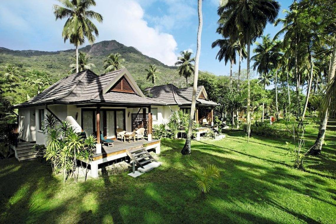 Außenansicht des Hilton Seychelles Labriz Resort & Spa mit zwei Chalets, umgeben von Palmen und grüner Landschaft.