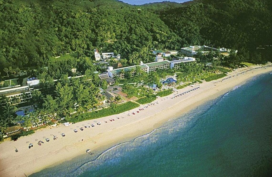 Luftaufnahme des Katathani Phuket Beach Resorts an einem Strand mit vielen Bäumen und Gebäuden.