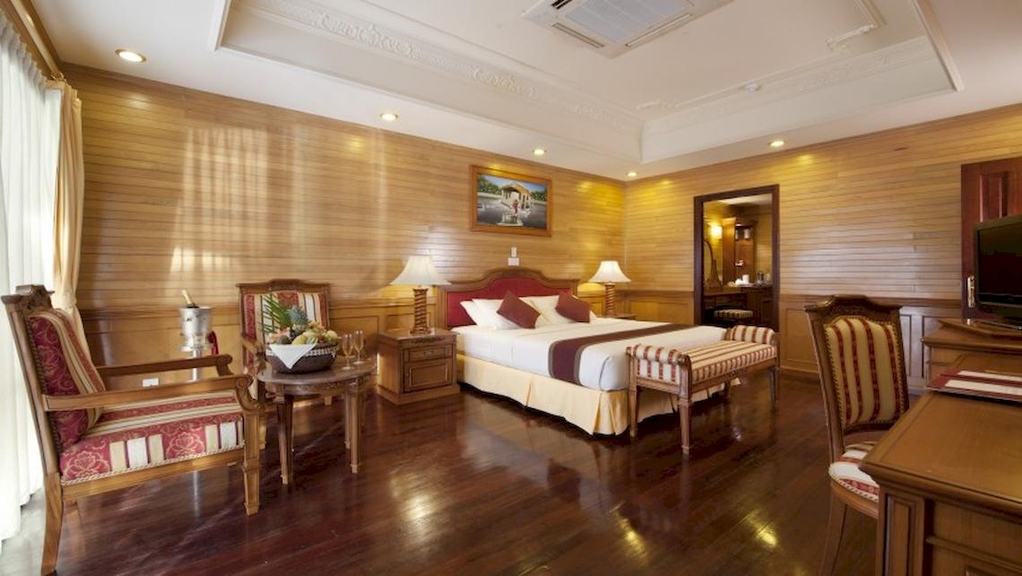Schlafzimmer im Royal Island Resort & Spa mit einem großen Bett, Holzmöbeln und einer Gemälde an der Wand.
