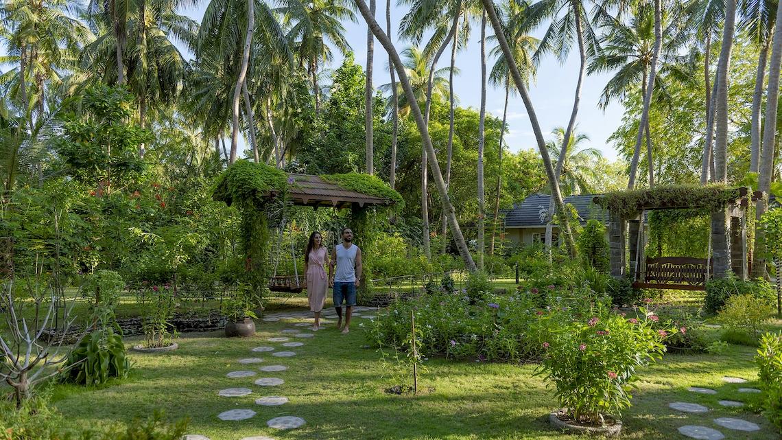 Ein Paar geht auf einem gepflasterten Weg im Garten des Royal Island Resort & Spa.