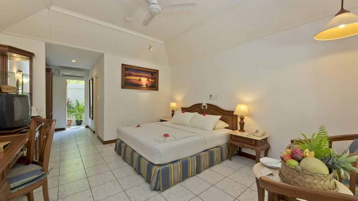 Hotelzimmer im Royal Island Resort & Spa mit Bett, Tisch, Fernseher und Früchtekorb