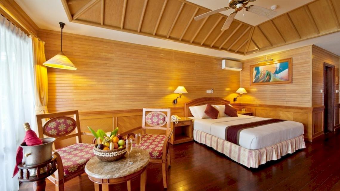 Hotelzimmer im Royal Island Resort & Spa mit Bett, Obstkorb, Stühle und Deckenventilator.