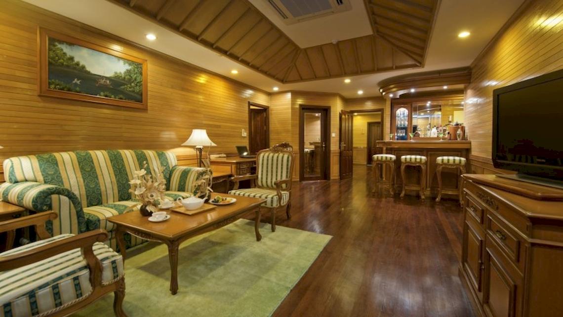 Das Wohnzimmer des Royal Island Resort & Spa mit Holzwänden, einem grünen Sofa, einem Tisch und einer Fernseher.
