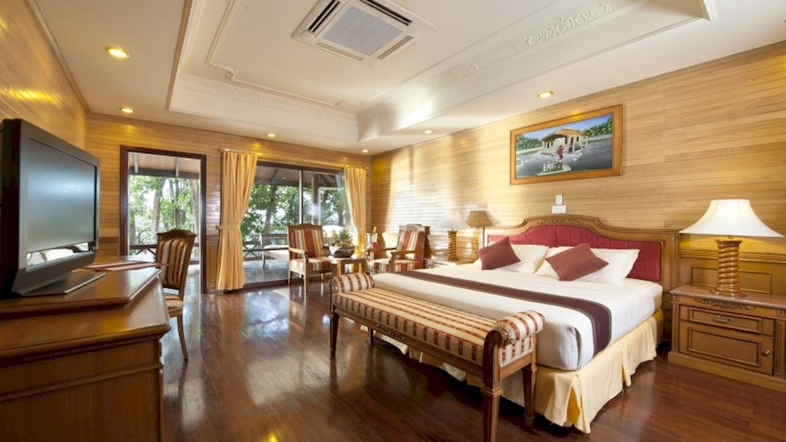 Hotelzimmer im Royal Island Resort & Spa mit Fernseher, Bett, Möbeln und Panoramafenstern.