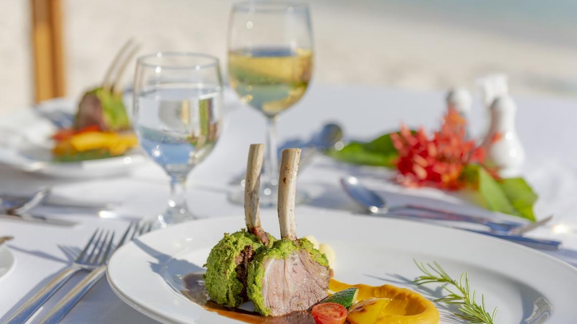 Eine Mahlzeit im Royal Island Resort & Spa mit Gerichten, Gläsern und Dekoration am Strand.