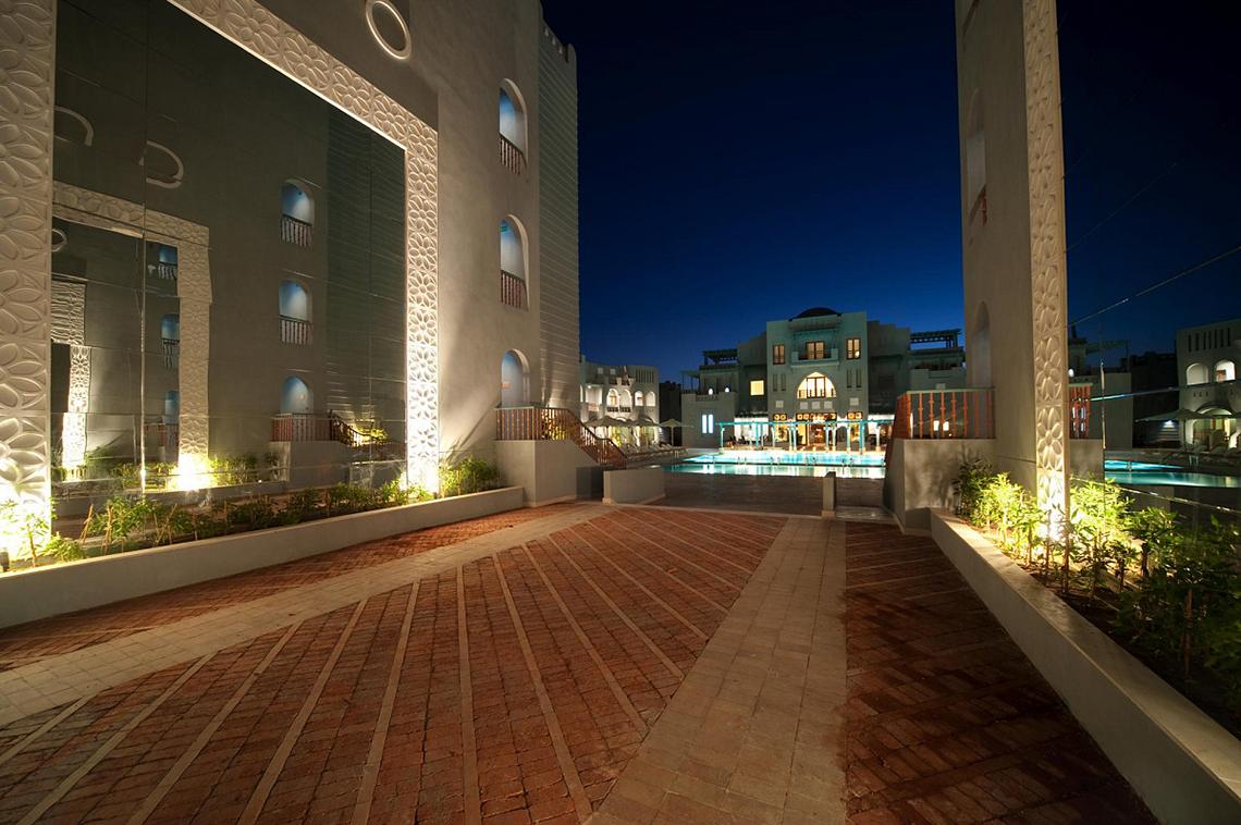 Abendlicher Blick auf das Fanadir Hotel El Gouna mit einem beleuchteten Innenhof und Swimmingpool.