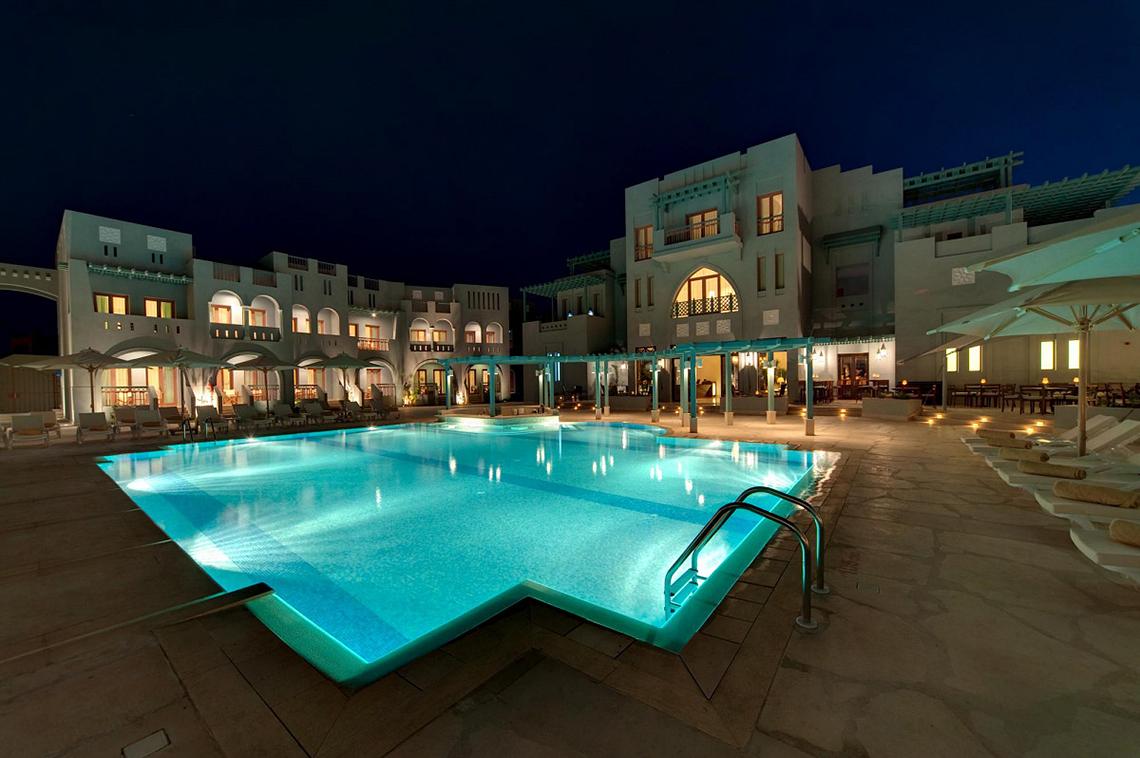 Der Außenpool des Fanadir Hotel El Gouna bei Nacht mit Loungestühlen und Sonnenschirmen