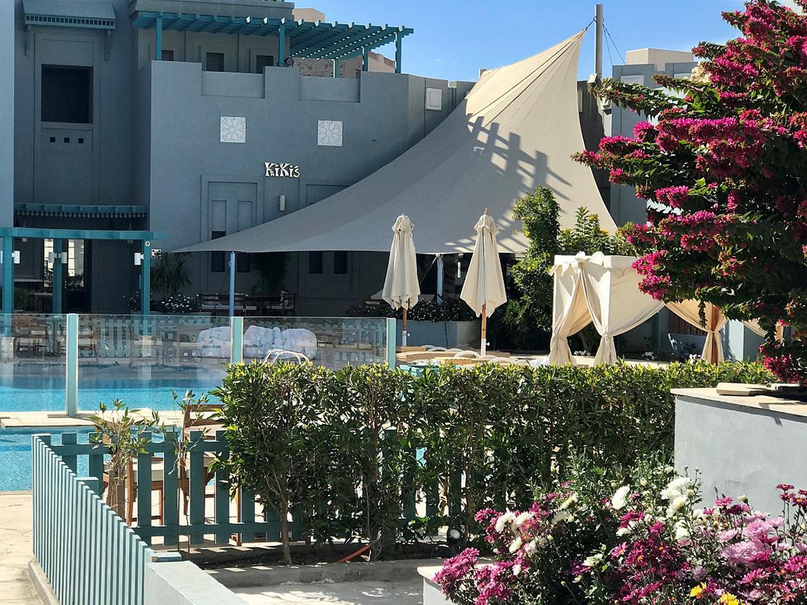 Außenbereich des Fanadir Hotel El Gouna mit Pool, Sonnenschirmen und Pflanzen.
