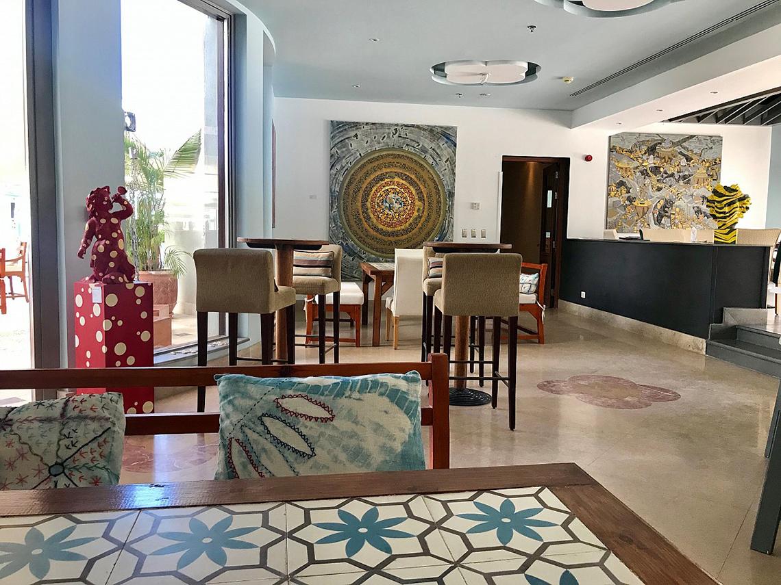 Lounge-Bereich des Fanadir Hotel El Gouna mit Barhockern, Kunstwerken und einem Tisch.