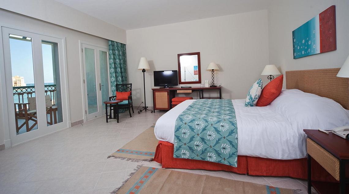 Fanadir Hotel El Gouna Zimmer mit Meerblick, Bett, Fernseher, Schreibtisch und Balkon.