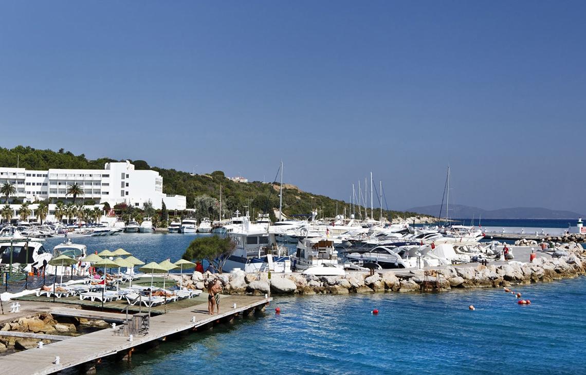 Altin Yunus Hotel & Spa Marina mit vielen Booten am Kai und Liegestühlen.