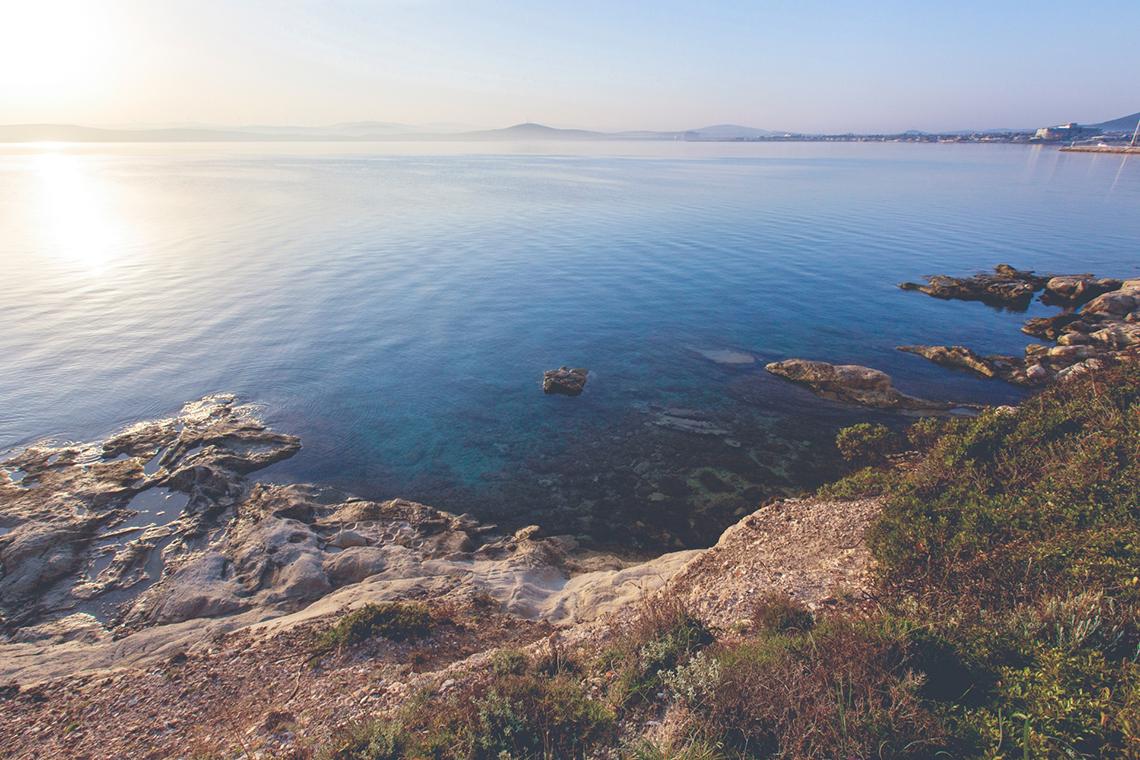 Aussicht auf das Meer und Felsen bei Sonnenaufgang mit sanften Wellen und Horizont