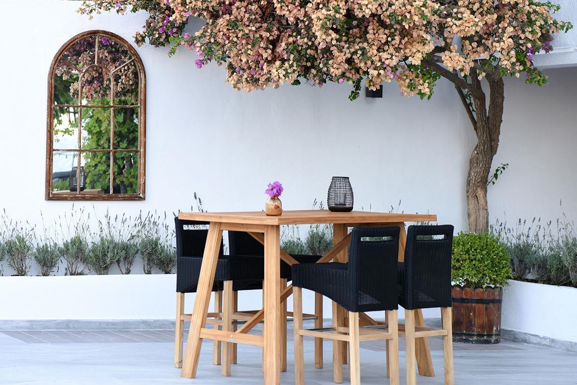 Holztisch im Garten des Altin Yunus Hotel & Spa mit vier Stühlen und einer Blumenvase.